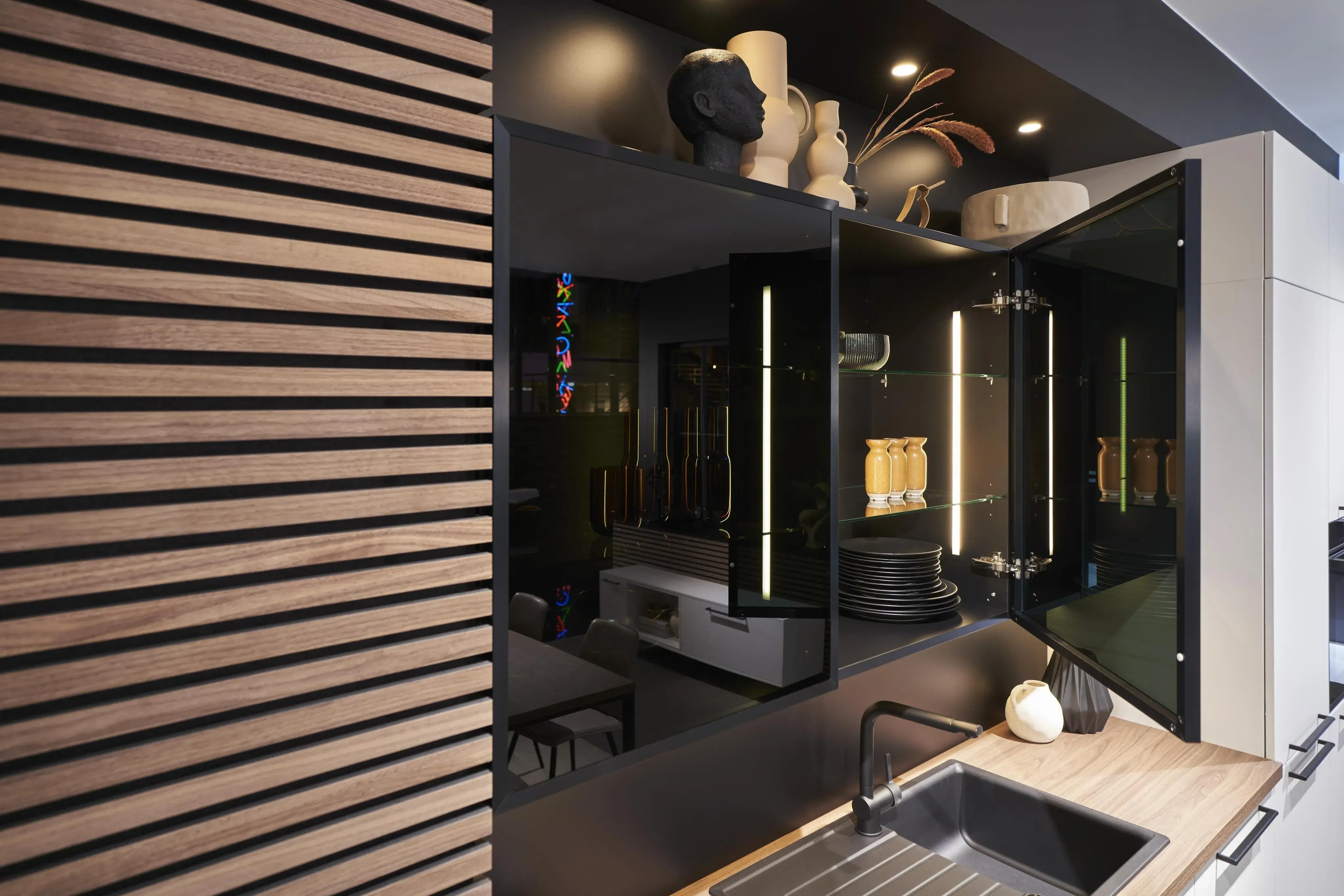 Glaswandschränke neben einem Holzpaneel und mit einer schwarzen Spüle